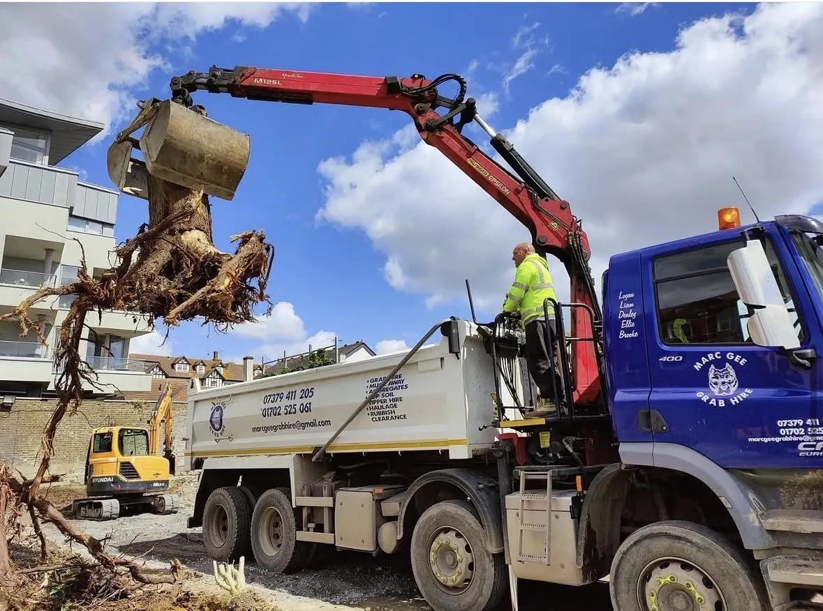 Grab lifting a large tree stump with roots on a building site