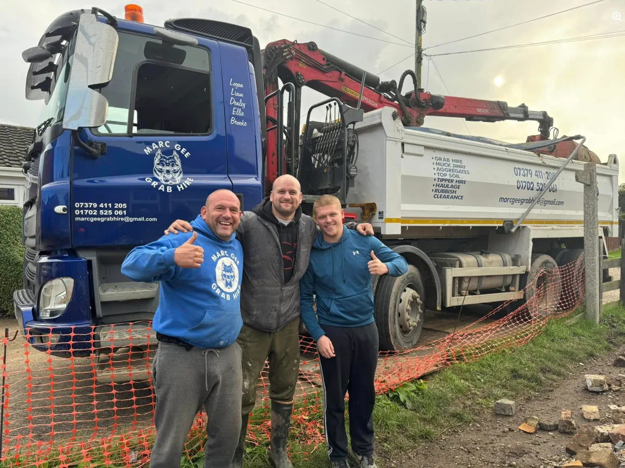 Three men smiling with thumbs up in front of a Marc Gee grab lorry on a job