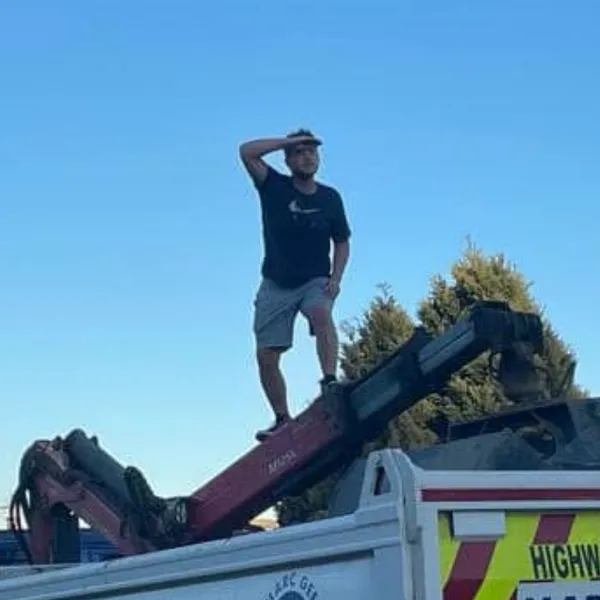 Liam standing on top of a Marc Gee grab lorry, shielding his eyes and looking into the distance